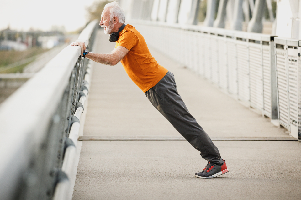 Older man doing an incline push-up against a railing, a beginner-friendly bodyweight strength move