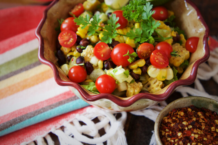 Colorful dish of tomatoes, corn, black beans and leafy greens, an example of a vegetable-rich balanced meal