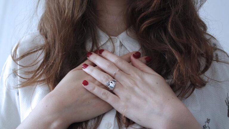 Woman holding both hands to her chest, illustrating chest pressure, a common heart attack warning sign