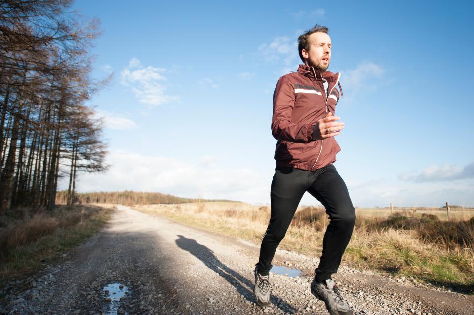 Man jogging along a country path under a blue sky, a heart-healthy habit for men