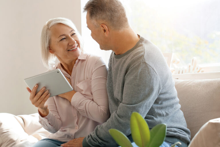 Smiling couple talking closely on a sofa at home, showing warm, open communication between partners