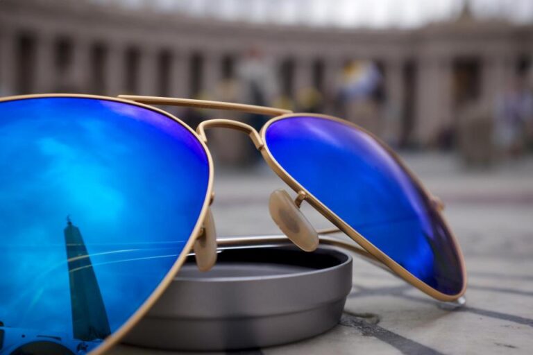 Aviator sunglasses with blue mirrored lenses resting on a sunlit outdoor surface