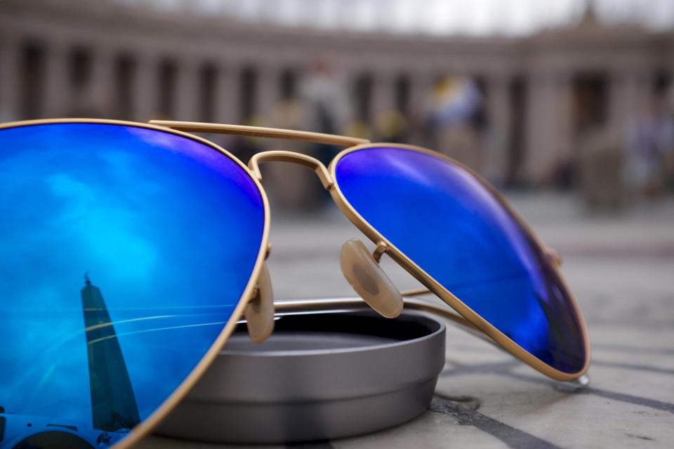 Aviator sunglasses with blue mirrored lenses resting on a sunlit outdoor surface