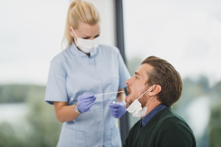 Nurse in a mask and gloves collecting a swab sample from a patient during a medical test