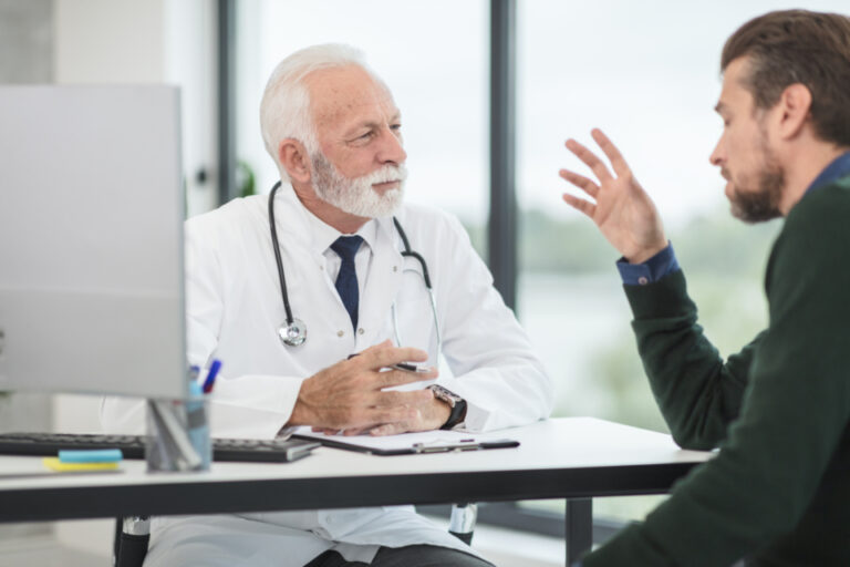 Doctor listening to a patient describe his symptoms during a consultation, as advised for suspected kidney stones