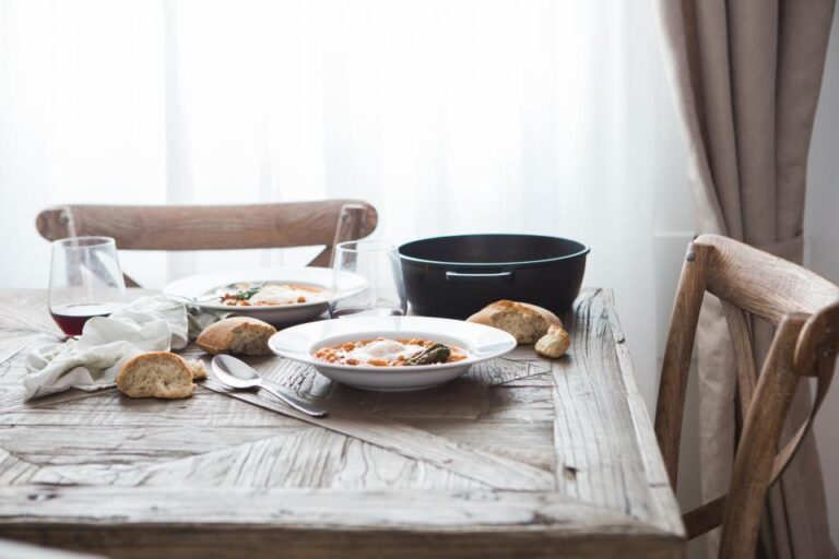 Calm dining table with bowls of food and bread by a bright window, set for an unhurried, mindful meal