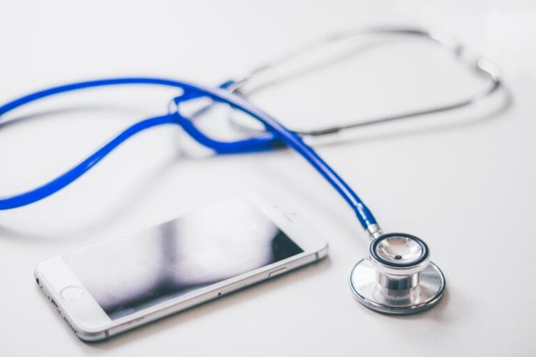 Stethoscope resting beside a smartphone on a white desk, ready for a preventive health checkup