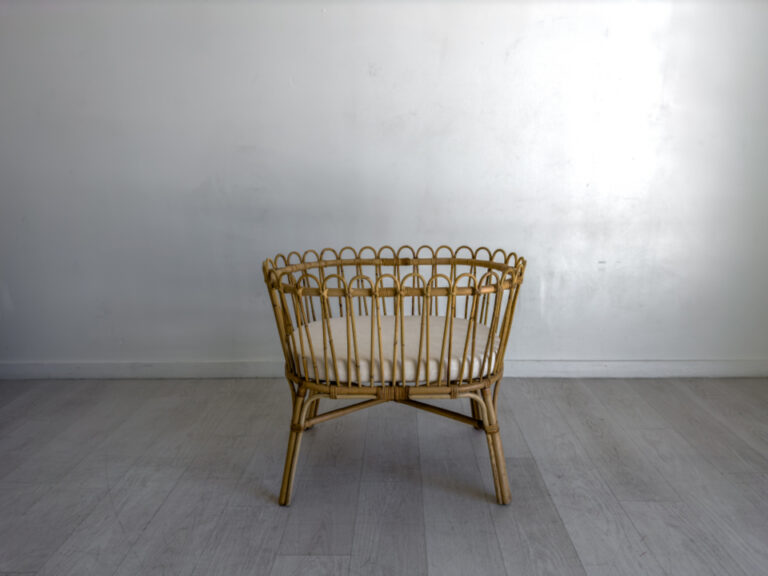 Empty wicker baby cradle in a bright room, an example of a clear, uncluttered sleep space for a baby