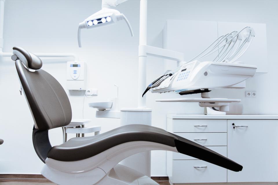 Modern dental treatment room with a dental chair and overhead light, where a dentist can check the cause of sensitive teeth