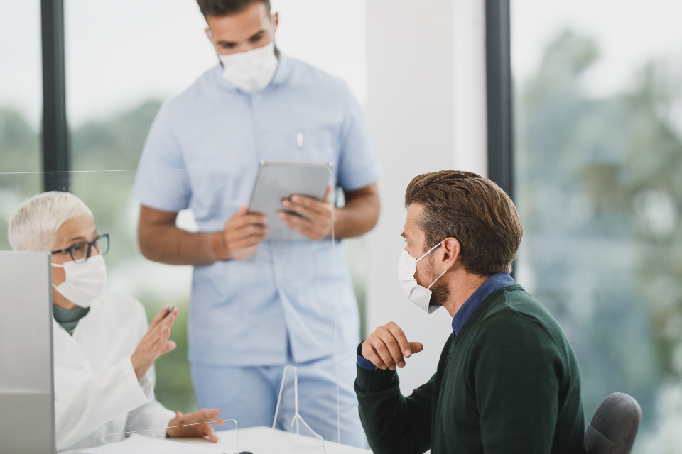 Clinicians talking with a patient at a clinic desk, where testing and screening options can be discussed